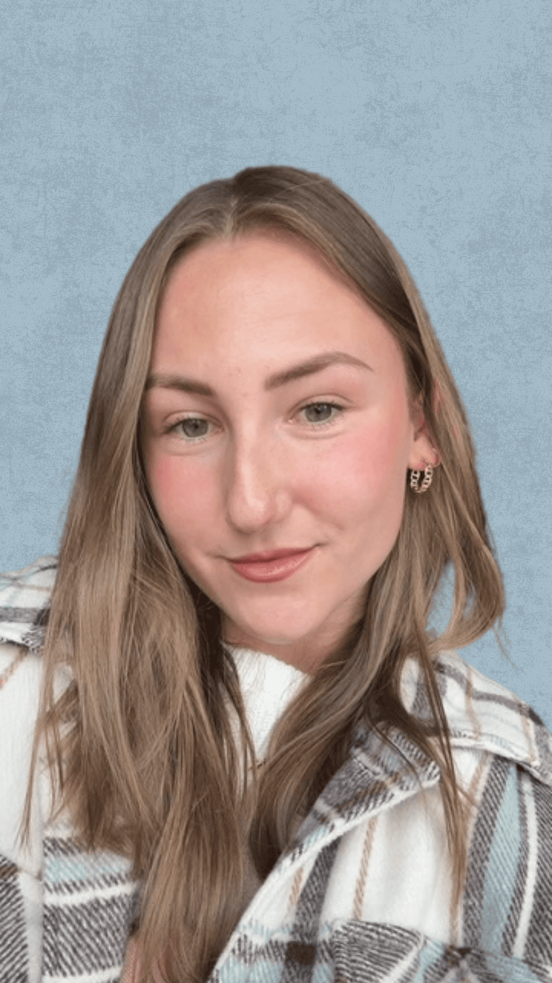 Headshot of a person with long light brown hair wearing a plaid jacket and gold earrings, against a light blue textured background.